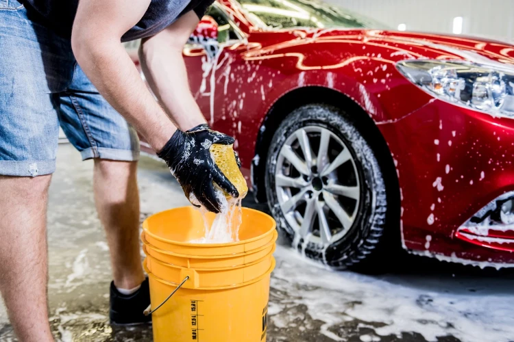 worker-washing-red-car-with-sponge-car-wash.webp